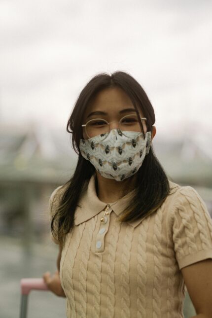 Teenage girl with eyeglasses wearing a patterned face mask outside.