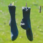 Woolen socks hung on a clothesline, drying in the sun with a natural green backdrop.