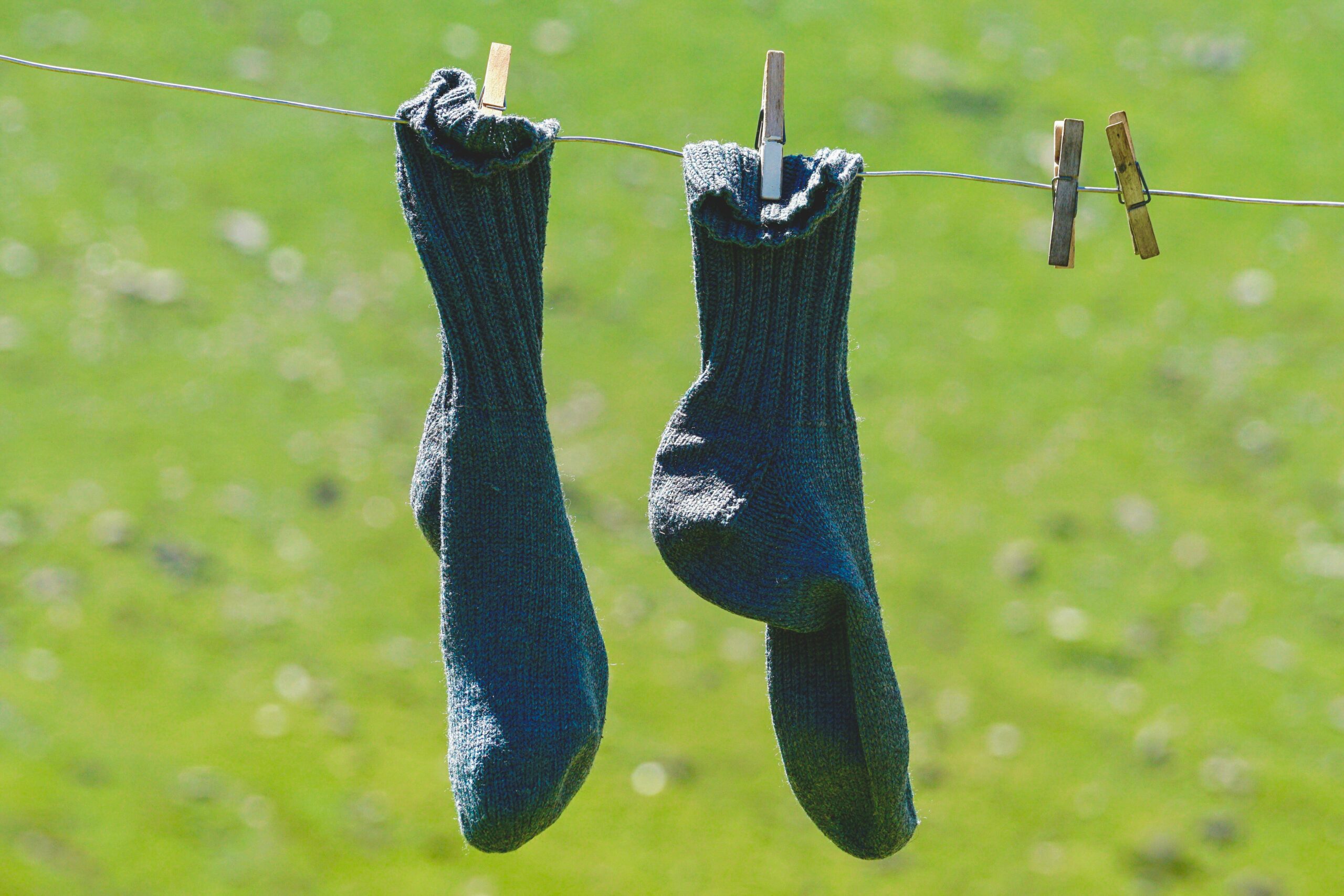 pexels-photo-1287513-1287513 Woolen socks hung on a clothesline, drying in the sun with a natural green backdrop.