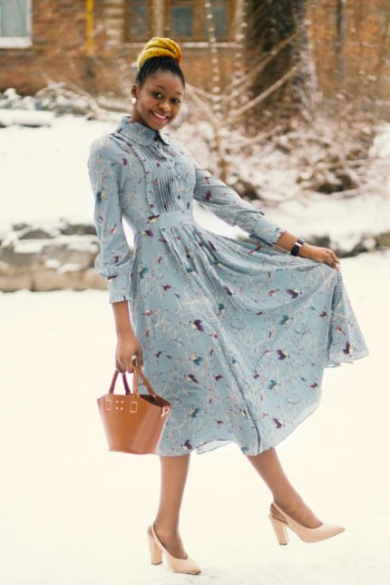 Charming woman in a floral dress enjoying a snowy winter day outdoors.