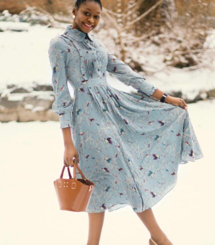 Charming woman in a floral dress enjoying a snowy winter day outdoors.