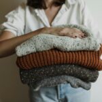 A woman holding a stack of cozy, warm knit sweaters, perfect for winter.