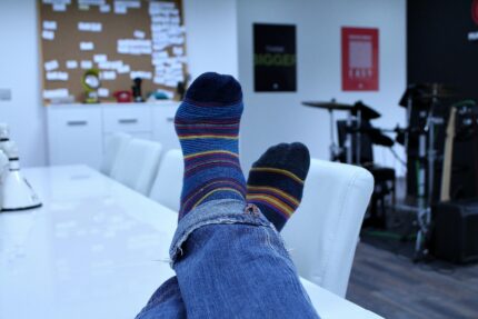 Relaxing in an office with colorful socks and blue jeans, showcasing casual comfort.