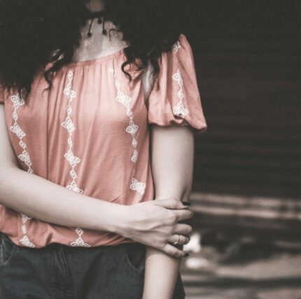 Stylish young woman in casual embroidered top in soft light.