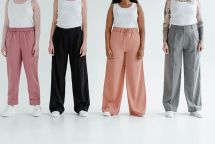 Four women stand in colorful trousers against a white background, showcasing diversity and fashion.